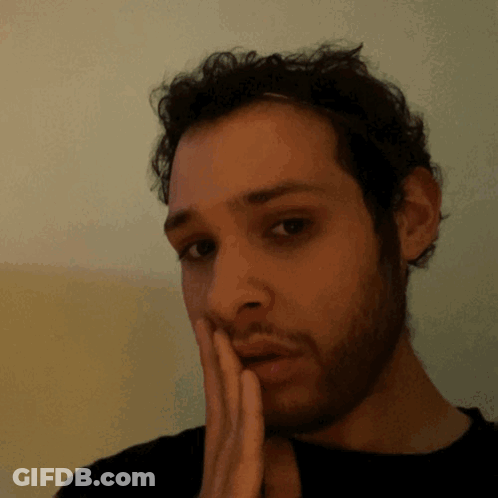 A Man With A Beard Has His Hand On His Chin GIF
