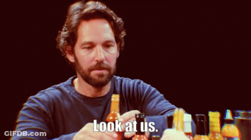 A Man With A Beard Holds A Bottle Of Hot Sauce And Says " Look At Us " GIF