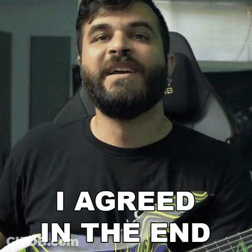 A Man With A Beard Holds A Guitar And Says I Agreed In The End GIF