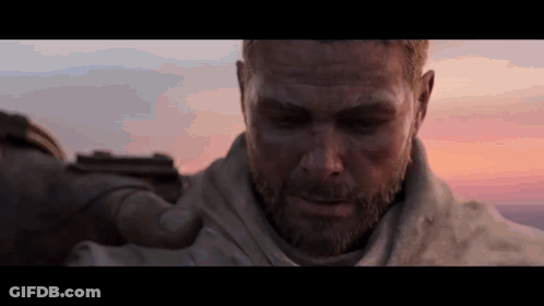 A Man With A Beard Holds A Gun In His Hand GIF