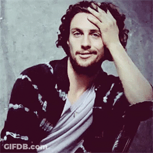 A Man With A Beard Holds His Hand To His Face GIF