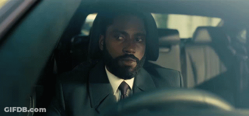 A Man With A Beard In A Suit And Tie Is Driving A Car GIF