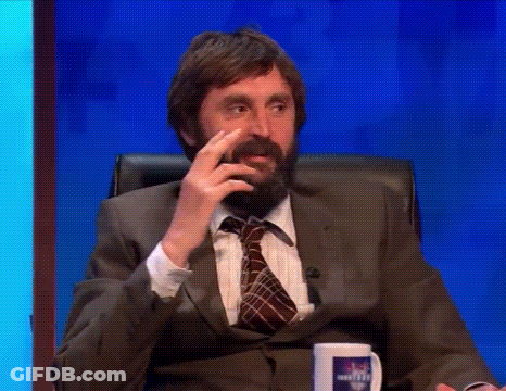 A Man With A Beard In A Suit And Tie Is Sitting In A Chair Talking On A Television Show . GIF