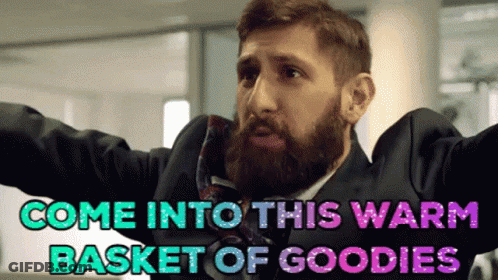 A Man With A Beard In A Suit And Tie Says " Come Into This Warm Basket Of Goodies " GIF