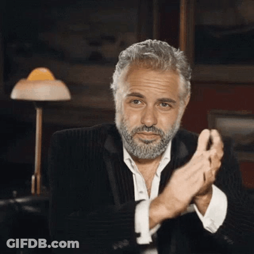 A Man With A Beard In A Suit Is Clapping His Hands . GIF