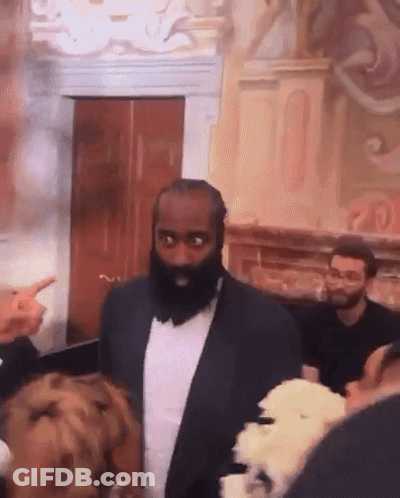 A Man With A Beard In A Suit Stands In Front Of A Group Of People GIF