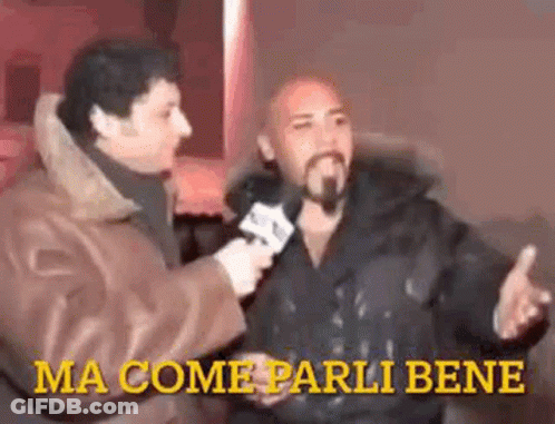 A Man With A Beard Is Being Interviewed By Another Man While Holding A Microphone . GIF