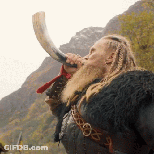 A Man With A Beard Is Blowing A Horn In Front Of Mountains GIF