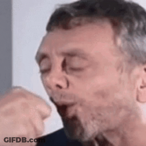 A Man With A Beard Is Blowing A Kiss . GIF