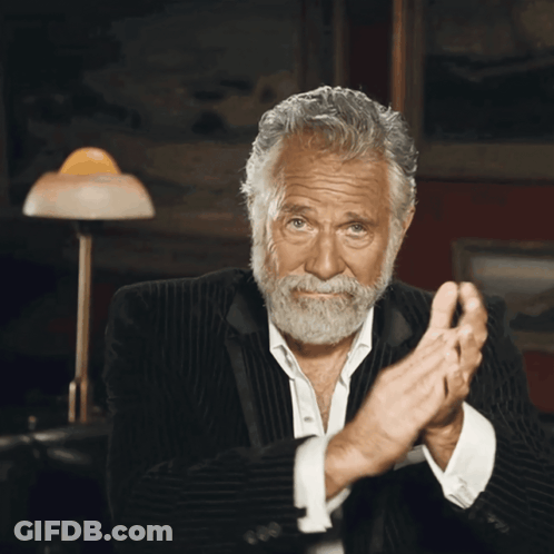 A Man With A Beard Is Clapping His Hands In A Dark Room GIF