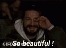 A Man With A Beard Is Covering His Eyes While Watching A Movie And The Words `` So Beautiful '' Are Above Him . GIF