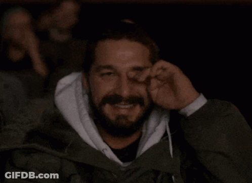 A Man With A Beard Is Covering His Face With His Hand GIF