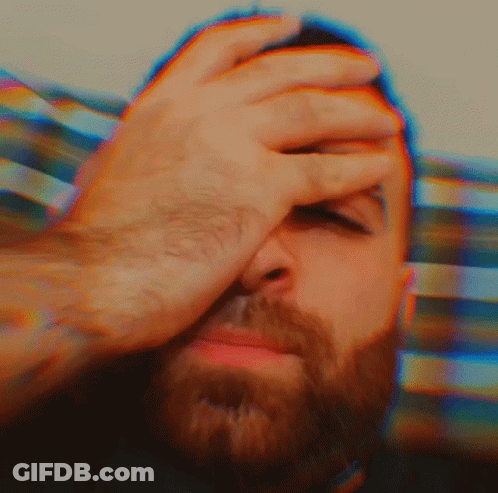 A Man With A Beard Is Covering His Face With His Hands GIF