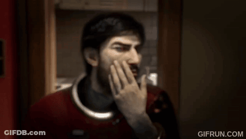 A Man With A Beard Is Covering His Mouth With His Hand In A Room . GIF