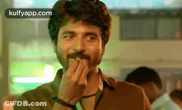 A Man With A Beard Is Covering His Mouth With His Hands . GIF