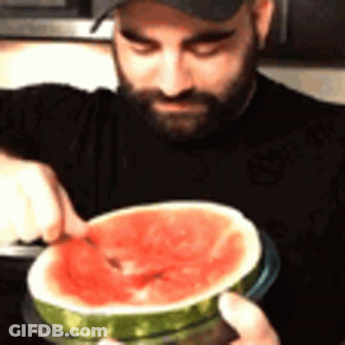 A Man With A Beard Is Cutting A Slice Of Watermelon GIF