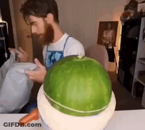 A Man With A Beard Is Cutting A Watermelon In Half GIF