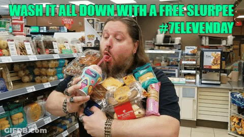 A Man With A Beard Is Drinking A Slurpee From A Straw In A Store GIF
