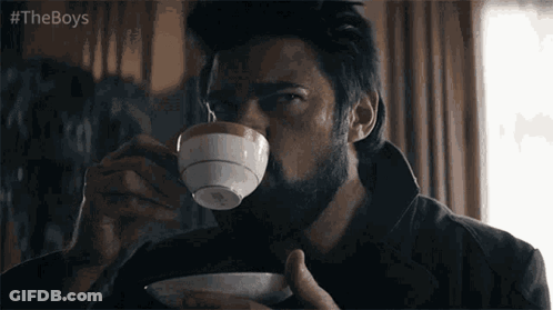 A Man With A Beard Is Drinking From A Cup Of Coffee . GIF
