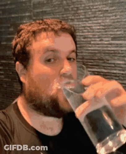A Man With A Beard Is Drinking From A Glass GIF