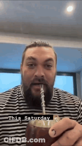 A Man With A Beard Is Drinking Through A Straw From A Coconut . GIF