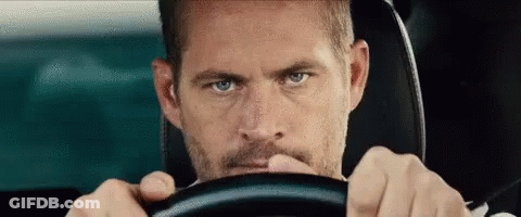 A Man With A Beard Is Driving A Car . GIF