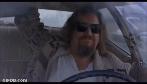 A Man With A Beard Is Driving A Car And Wearing Sunglasses . GIF