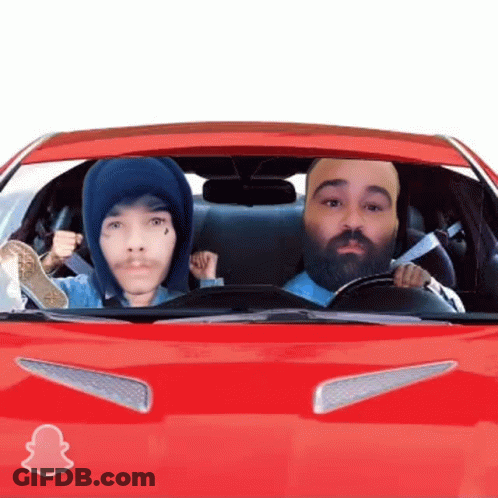 A Man With A Beard Is Driving A Red Car With A Snapchat Logo On The Hood GIF