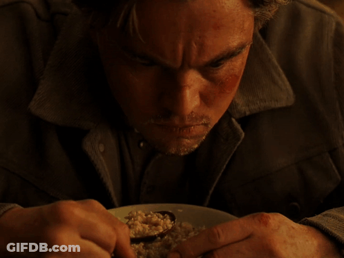 A Man With A Beard Is Eating A Plate Of Food With A Spoon GIF
