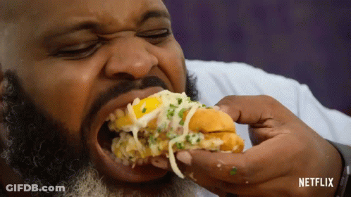 A Man With A Beard Is Eating A Sandwich With Netflix Written In The Corner GIF