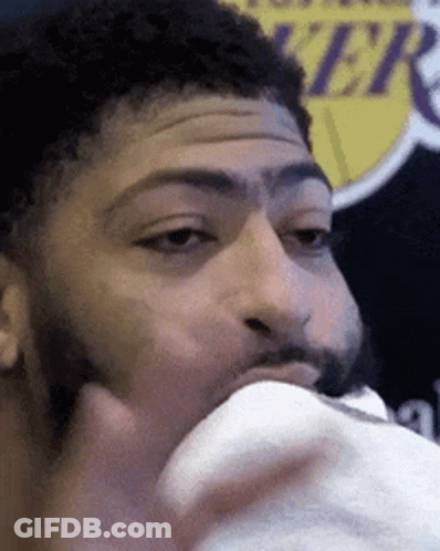 A Man With A Beard Is Eating Something In Front Of A Lakers Sign GIF