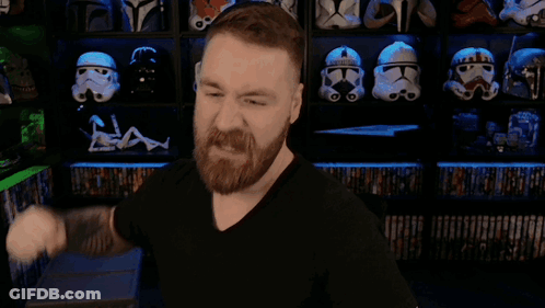 A Man With A Beard Is Flexing His Muscles In Front Of A Shelf Full Of Storm Trooper Helmets GIF
