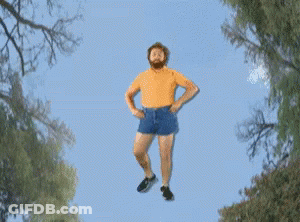 A Man With A Beard Is Flying Through The Air With His Arms Outstretched GIF
