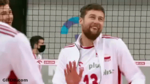 A Man With A Beard Is Giving A High Five To Another Man While Wearing A Volleyball Uniform . GIF