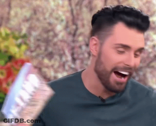 A Man With A Beard Is Holding A Bottle Of Water In His Hand And Smiling . GIF