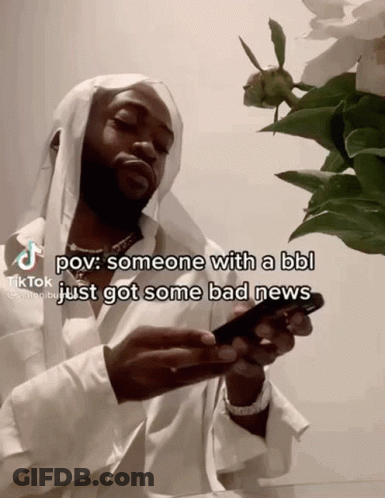 A Man With A Beard Is Holding A Cell Phone In Front Of A Flower . GIF