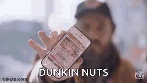 A Man With A Beard Is Holding A Cell Phone In His Hand . GIF