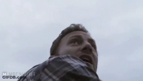A Man With A Beard Is Holding A Chainsaw In His Hands . GIF