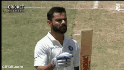 A Man With A Beard Is Holding A Cricket Bat On A Field GIF