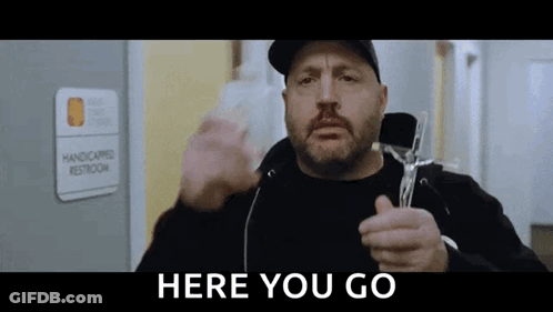 A Man With A Beard Is Holding A Cross In Front Of A Handicapped Restroom . GIF