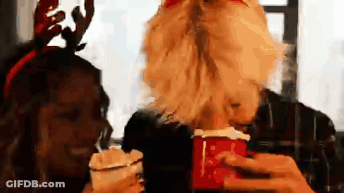 A Man With A Beard Is Holding A Cup Of Hot Chocolate Next To A Woman Wearing Antlers . GIF