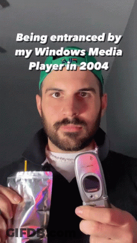 A Man With A Beard Is Holding A Flip Phone And A Bag Of Food GIF
