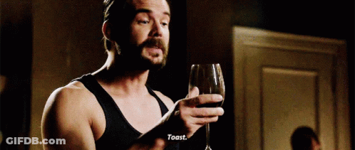 A Man With A Beard Is Holding A Glass Of Wine And Toasting GIF