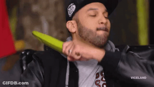 A Man With A Beard Is Holding A Green Object To His Neck . GIF