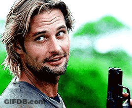 A Man With A Beard Is Holding A Gun And Smiling . GIF