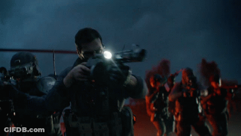 A Man With A Beard Is Holding A Gun With A Light On It GIF