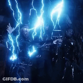A Man With A Beard Is Holding A Hammer And Being Struck By Lightning In A Dark Room . GIF