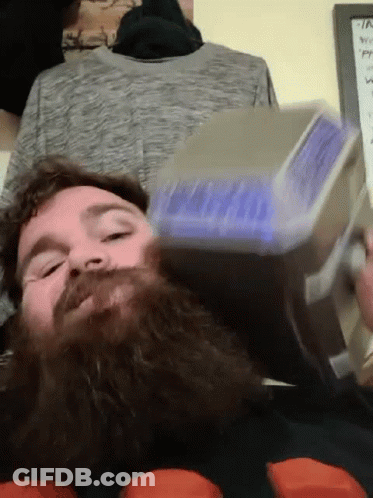 A Man With A Beard Is Holding A Hammer In His Hand GIF