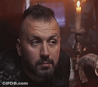 A Man With A Beard Is Holding A Knife In His Hand GIF