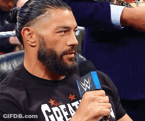 A Man With A Beard Is Holding A Microphone And Wearing A T-Shirt That Says Great GIF